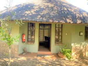 a small house with a thatched roof and a red fire hydrant at Double lodge on natural African bush - 2112 in Bulawayo