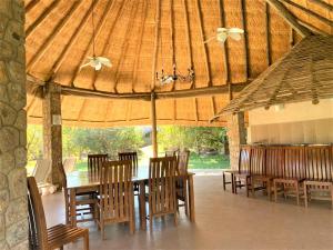 a dining room with a table and chairs in a pavilion at Family Lodge in Natural African bush - 2113 in Bulawayo