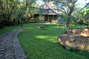 a stone path leading to a house with a tree at Family Lodge in Natural African bush - 2113 in Bulawayo