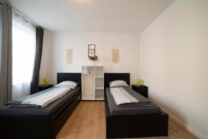 2 camas en una habitación con paredes blancas en Schöne Ferienwohnung 78m2, 3 Schlafzimmer, 2 Bäder, Zentrumnah, 1OG, en Erfurt