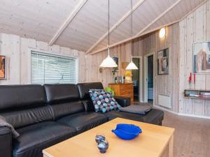 a living room with a black leather couch and a table at 8 person holiday home in Hemmet in Falen