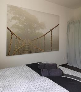 a bedroom with a painting of a suspension bridge at Aux portes de Nantes, 2 pièces moderne et confortable in Carquefou