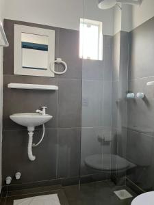 La salle de bains est pourvue d'un lavabo et d'une douche en verre. dans l'établissement Pousada Silvestre, à Tramandaí