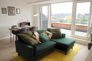 a living room with a green couch and a large window at Penthouse by the Ipswich Station in Ipswich