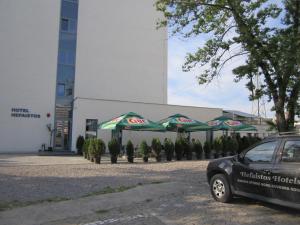 瑪美亞的住宿－馬馬亞赫法伊斯托斯酒店，停在大楼前的带遮阳伞的停车场