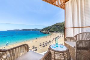 Blick auf einen Strand mit Stühlen und einem Tisch in der Unterkunft El Somni Ibiza Dream Hotel by Grupotel in Sant Joan de Labritja