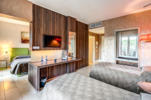 a bedroom with two beds and a tv on a wall at Hotel Isola Sacra Rome Airport in Fiumicino