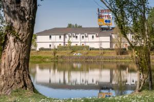 a large white building next to a body of water at The Originals Access, Hôtel Bordeaux Lac in Bruges