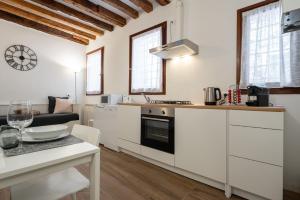 a kitchen with white cabinets and a table with a counter top at Suite Ravà - San Marco with pool in Venice