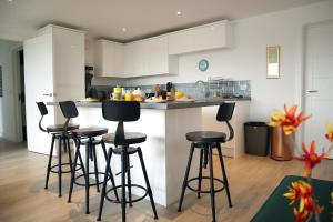 a kitchen with four bar stools in a kitchen at Penthouse by the Ipswich Station in Ipswich