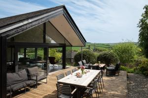 una terraza de madera con mesa de comedor y sillas en Quarry House, en Kingsbridge