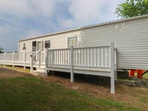 a white mobile home with a porch and a fence at Chez Nous in Newquay +7 photos