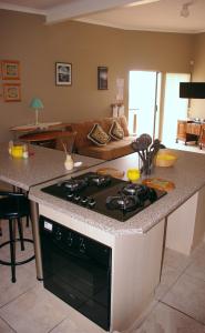 a kitchen with a stove top oven in a living room at The Third Dolphin in Herolds Bay