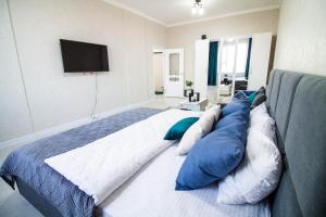 Schlafzimmer mit einem Bett mit blauen und weißen Kissen in der Unterkunft AB Apart Business 64305 in Astana