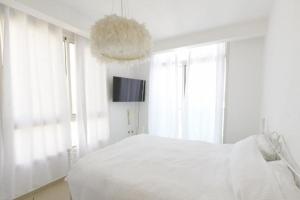 a white bedroom with a bed and a chandelier at Modern 2BR APT Golf Residence in Eilat +22 photos