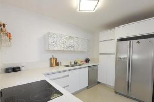 a kitchen with white cabinets and a stainless steel refrigerator at Modern 2BR APT Golf Residence in Eilat