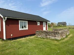 a red house with a stone wall in front of it at Red cozy cottage with sea view in Mörbylånga