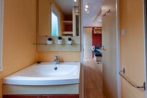 La salle de bains est pourvue d'un lavabo blanc et d'un miroir. dans l'établissement L'Eucalyptus, mobil-home avec extérieur spacieux à quelques mètres de la mer, à Hyères