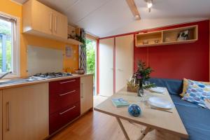 a kitchen with a table and a couch in a room at L'Eucalyptus, mobil-home avec extérieur spacieux à quelques mètres de la mer in Hyères