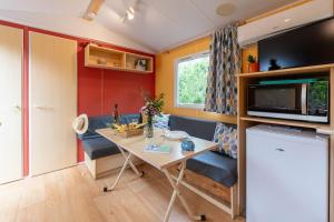 a small living room with a table and a microwave at L'Eucalyptus, mobil-home avec extérieur spacieux à quelques mètres de la mer in Hyères