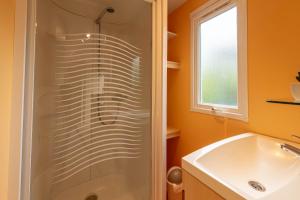 uma casa de banho com um chuveiro e um lavatório branco em L'Eucalyptus, mobil-home avec extérieur spacieux à quelques mètres de la mer em Hyères