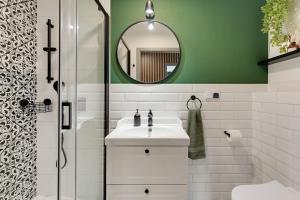 a bathroom with a white sink and a green wall at Flatbook - City Center Apartments Angielska Grobla in Gdańsk