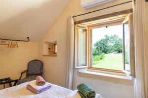 a bedroom with a window and a bed and a chair at Chambre d'hotes La Grange Milou in Beynac-et-Cazenac