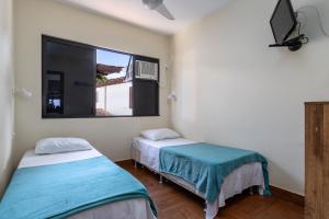 two beds in a room with a window at Apart Hotel Pet Friendly em Búzios in Búzios