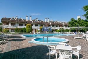 einen Pool in einem Resort mit Tischen und Stühlen in der Unterkunft Residence Equilio in Lido di Jesolo