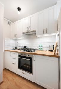a white kitchen with white cabinets and a stove at Ochota Standard Apartment in Warsaw