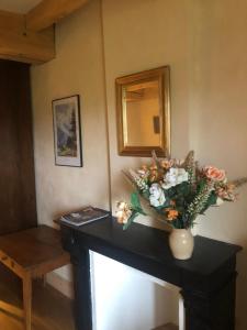 eine Vase mit Blumen auf einem Tisch in einem Zimmer in der Unterkunft L’ABSINTHE 