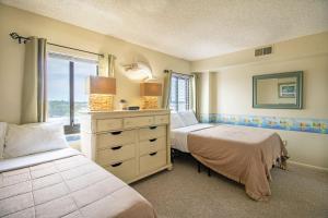 a bedroom with two beds and a dresser and a window at The Colony at Virginia Beach by TripForth in Virginia Beach