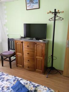 a room with a television on a wooden dresser with a lamp at Къща за гости Ганчеви in Sozopol