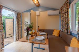 a living room with a table and a couch at La Doucette, mobil-home climatisé au cœur du vignoble et à 50m de la mer in Hyères