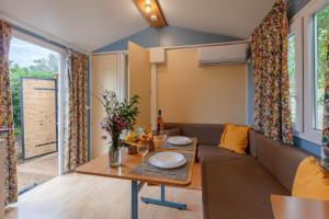 salon ze stołem i kanapą w obiekcie La Doucette, mobil-home climatisé au cœur du vignoble et à 50m de la mer w Hyères