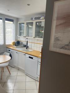 een keuken met witte kasten, een wastafel en een tafel bij Le mûrier - 2 chambres chez l'habitant in Rhut