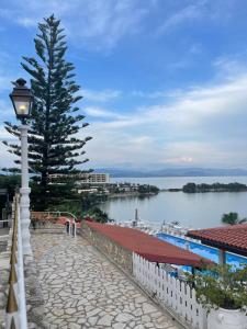 uma luz de rua ao lado de uma árvore e um corpo de água em Kommeno Bay Apartments em Corfu Town