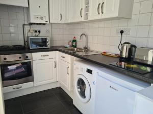 a kitchen with a sink and a washing machine at Cosy Cottage for work or leisure, RD&E 20min walk, easy access to city centre in Exeter