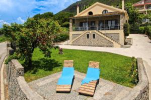 ParamonasにあるCorfu Villa Nikolasの背景に家屋とビーチチェア2脚