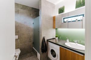 a bathroom with a sink and a washing machine at Butique Apartman in Balatonlelle