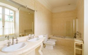 a bathroom with two sinks and a toilet and a tub at Hôtel de Margaux in Margaux