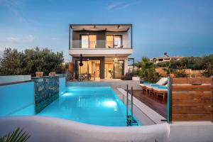 a villa with a swimming pool in front of a house at Aida Luxury Villas in Analipsi