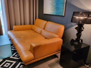 a brown leather couch in a living room with a lamp at Empire Damansara Designer Soho Karaoke & Netflix in Petaling Jaya