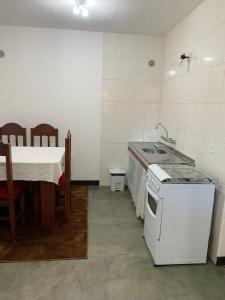 uma cozinha com um fogão, um lavatório e uma mesa em Casa da Inês em Monte Verde