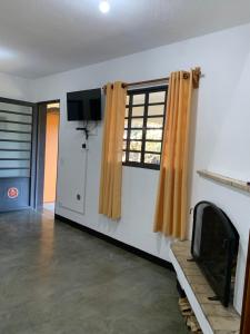 a living room with a tv and a window at Casa da Inês exclusiva para 01 ou 02 casais ou família in Monte Verde