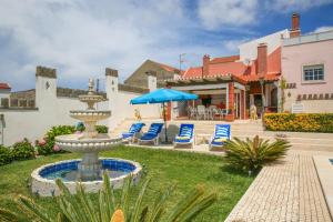Una fuente con sillas y una sombrilla en un patio. en Apartamento Vasco da Gama - Pool & BQQ - Pata da Gaivota, en Lourinhã