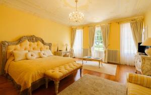 Un dormitorio con una cama con paredes amarillas y una lámpara de araña. en Hôtel de Margaux en Margaux