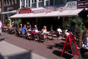 a group of people sitting at tables outside a restaurant at Hotel Central Hannover in Hannover