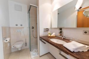 a bathroom with a sink and a toilet and a mirror at Parkhotel St.Leonhard in Überlingen