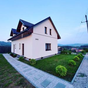 a white house on top of a green field at Domek Wilcze Wzgórze in Istebna